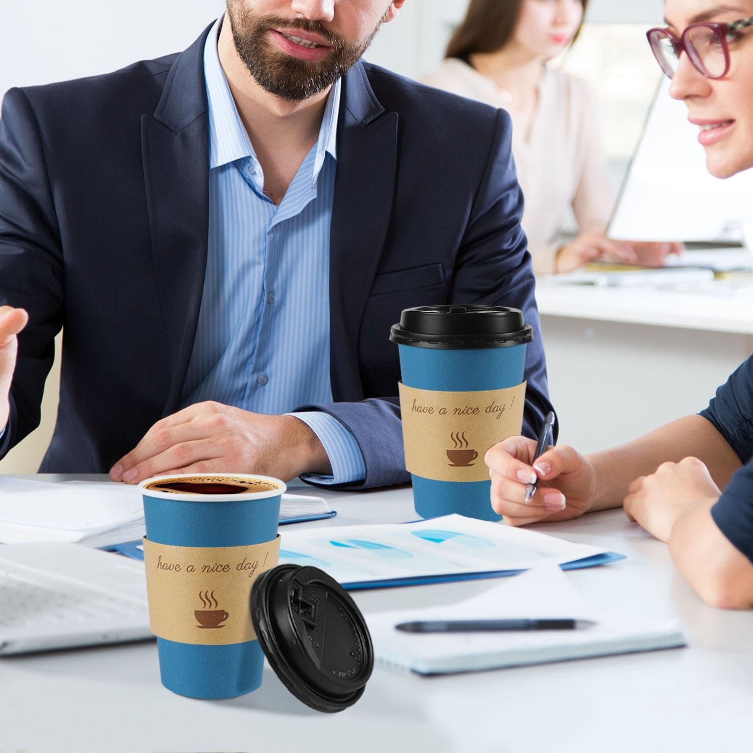 Paper coffee cups with kraft sleeves and black lids in an office setting